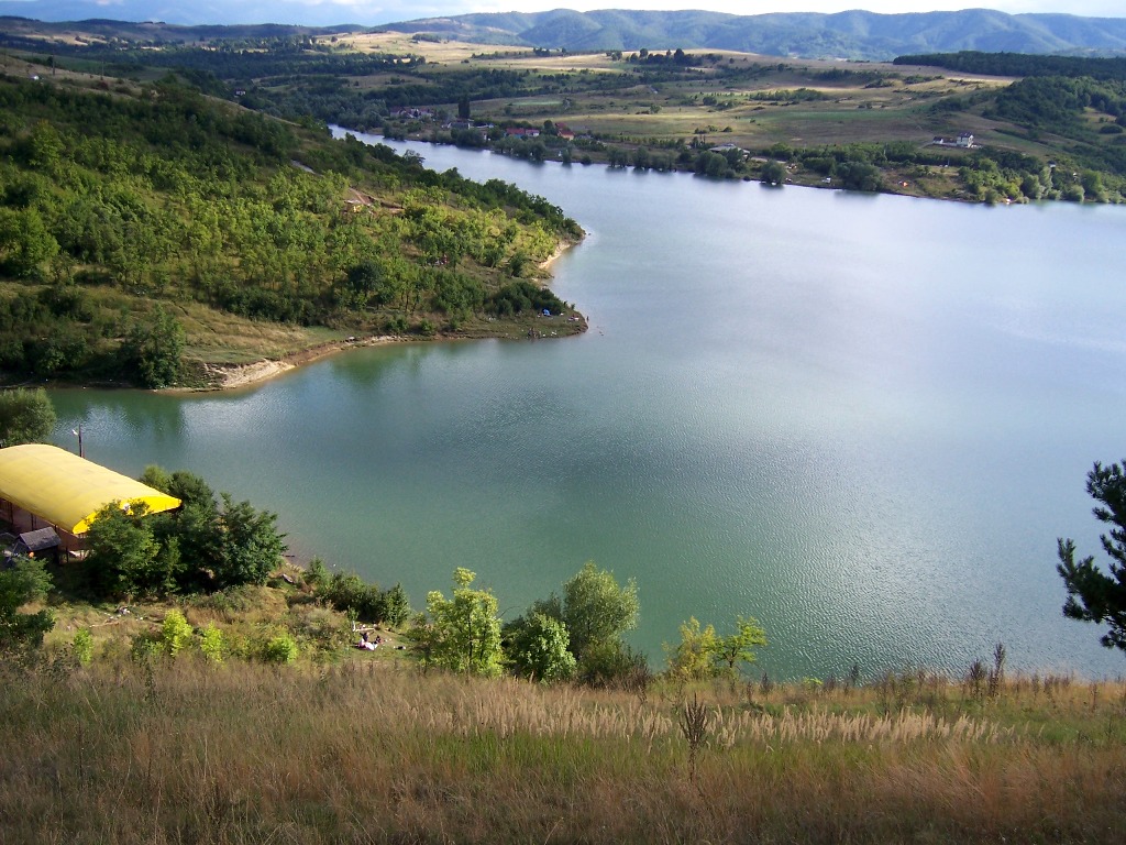 the landscape shows a blue body of water and trees