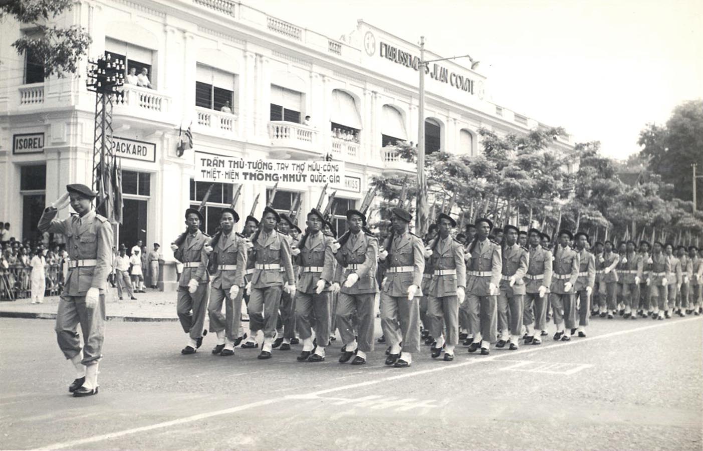 people in uniforms marching down the road with flags