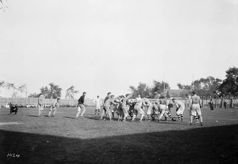 men running together while a man holding a ball approaches from the field