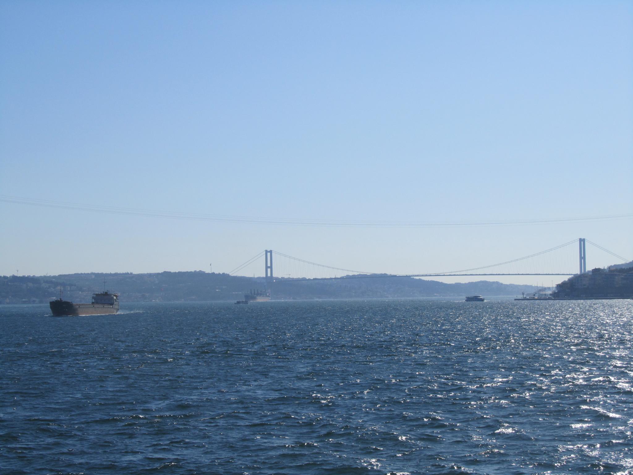 a large barge floats near a suspension bridge