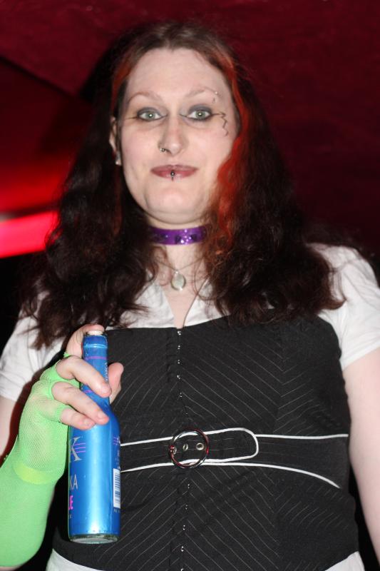 woman in cosplay holding a can and wearing green rubber gloves