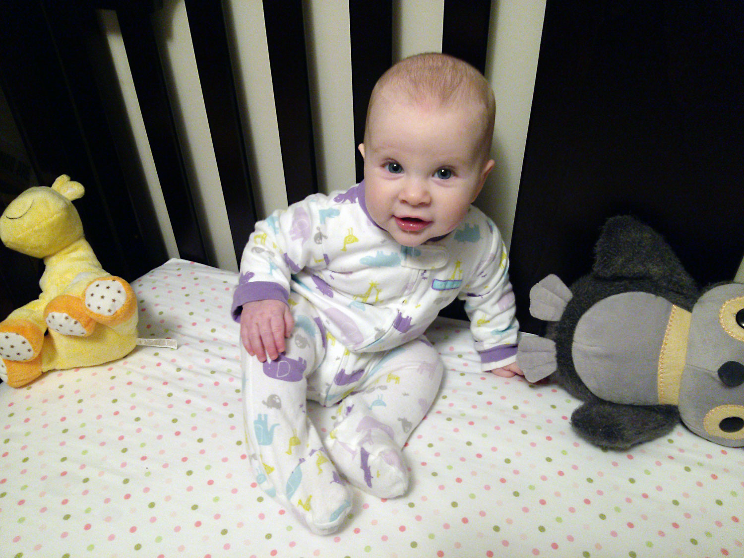 a baby wearing pajamas sitting on a bed