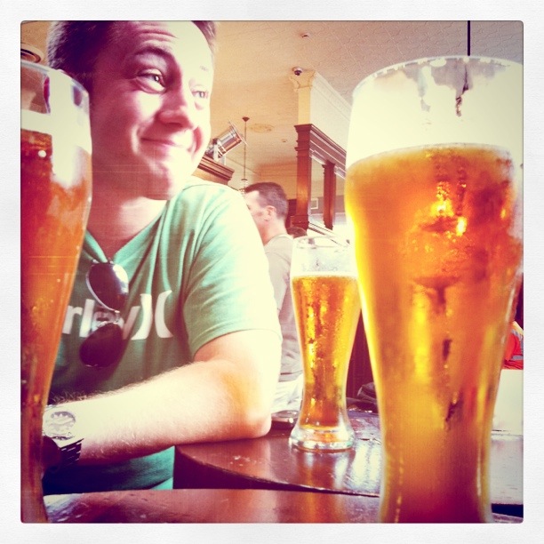 the man smiles at two different beers, one tall