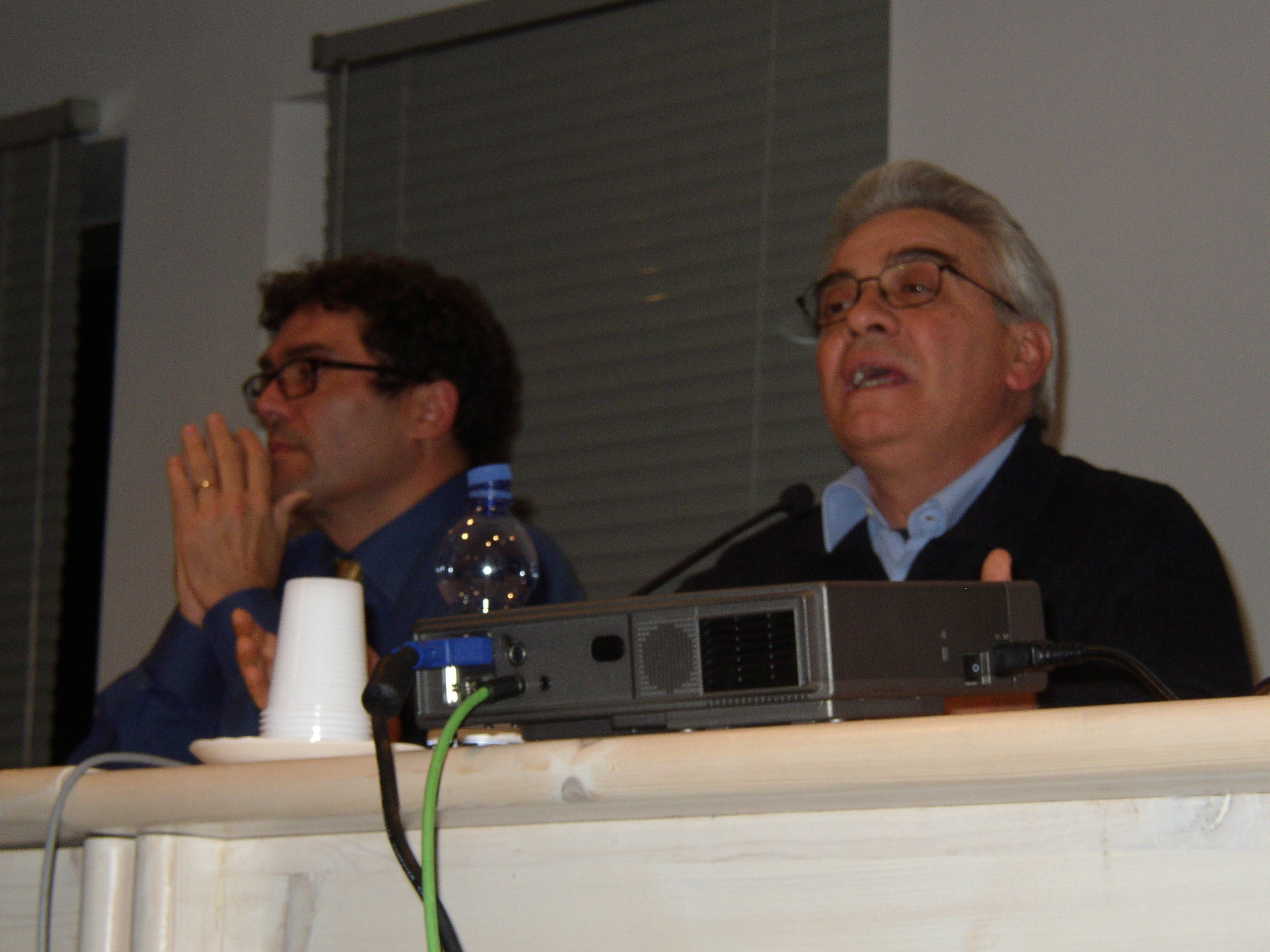 two men are sitting at a table with microphones