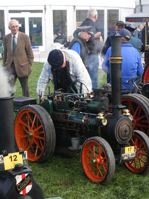 people stand around and look at an old, antique steam engine