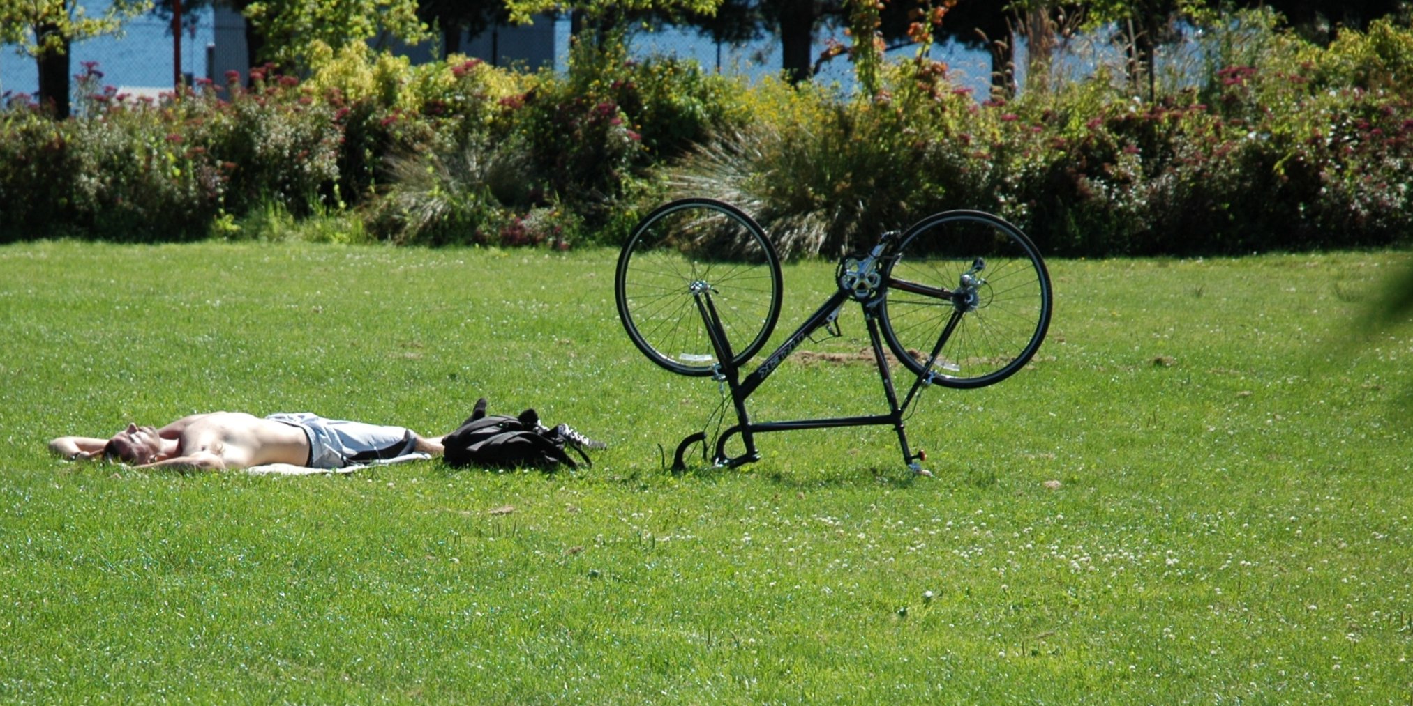 a man laying in the grass next to a black bike rack