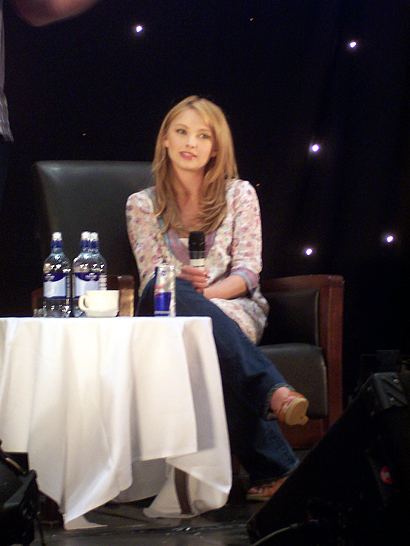 a man and woman sit at a table in front of a microphone