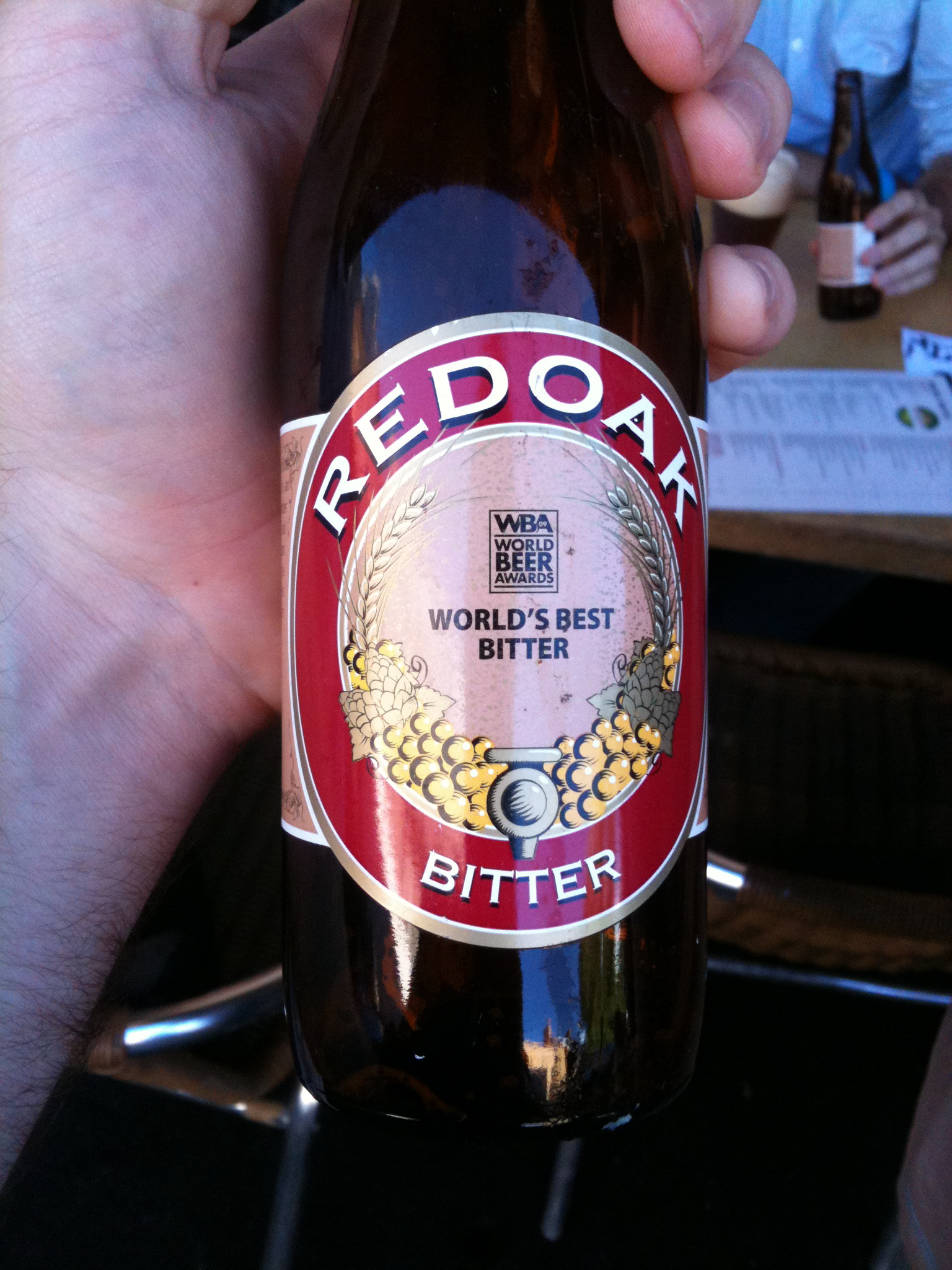 red oak bitter in a man's hand with a beer bottle