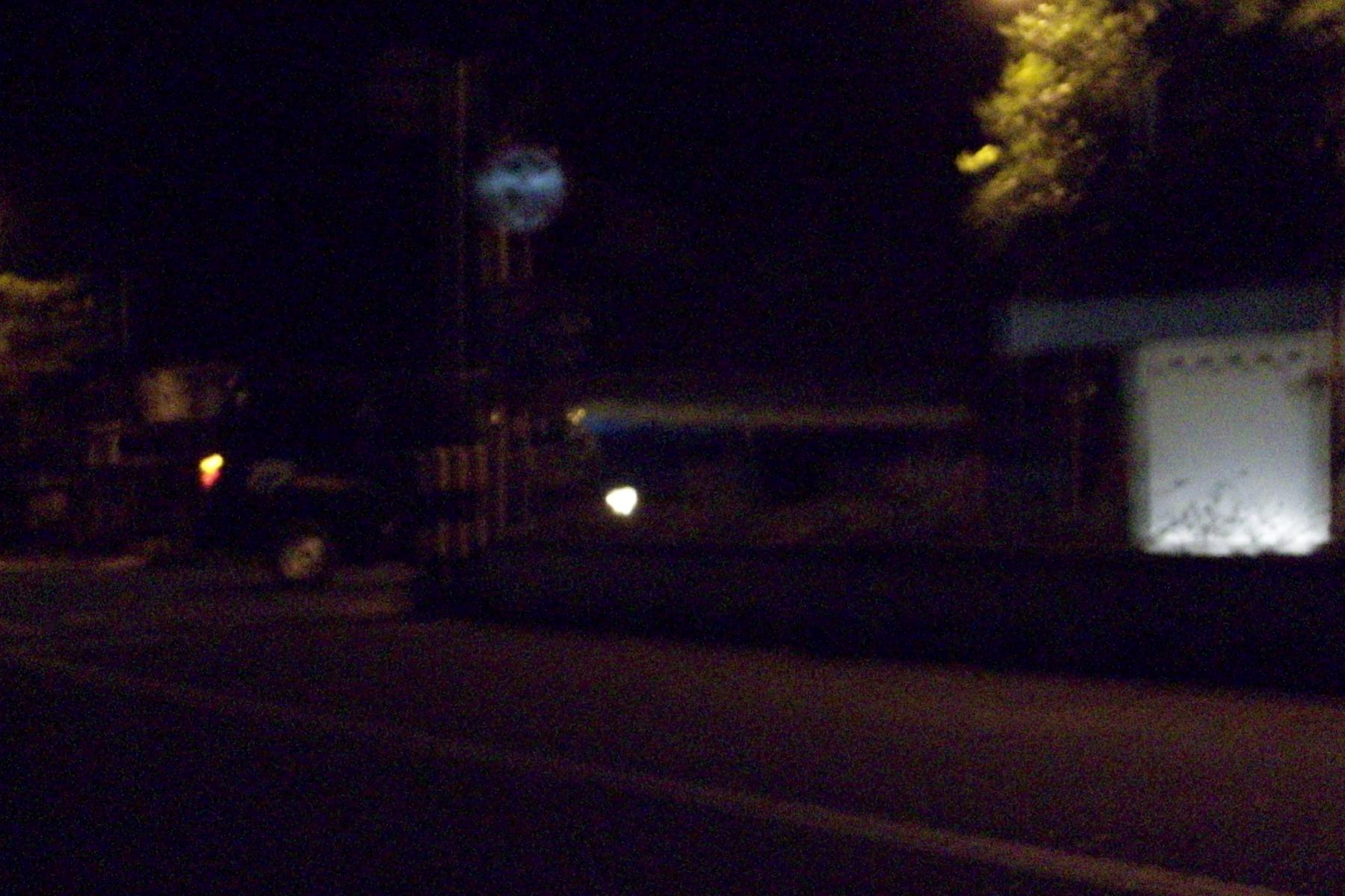 a dark street with a light sign and clock