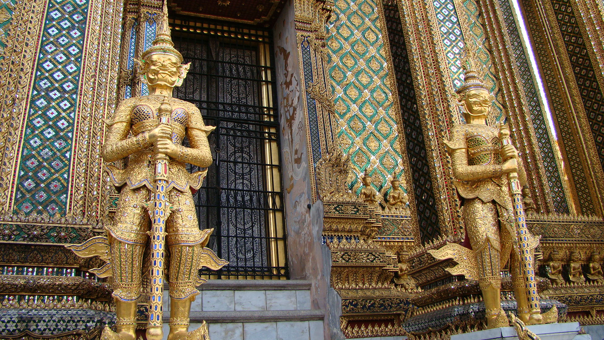 some gilded sculptures are standing outside a door