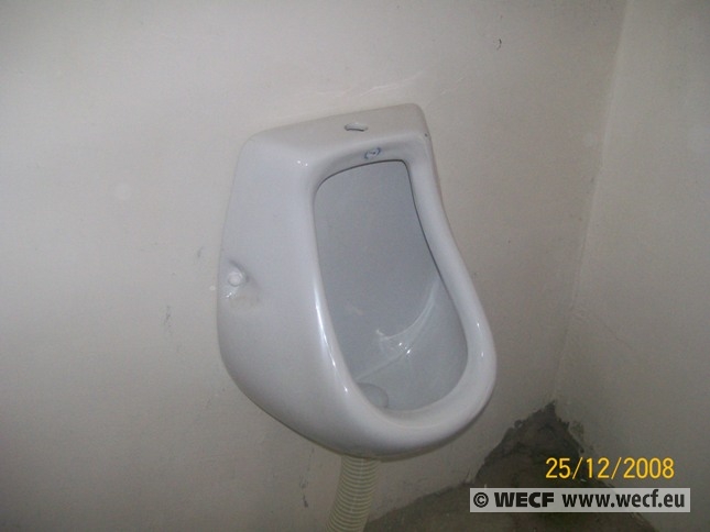 urinal attached to the wall in corner of public restroom