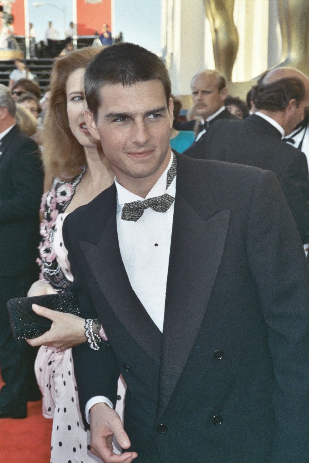 man in suit and bow tie standing on red carpet