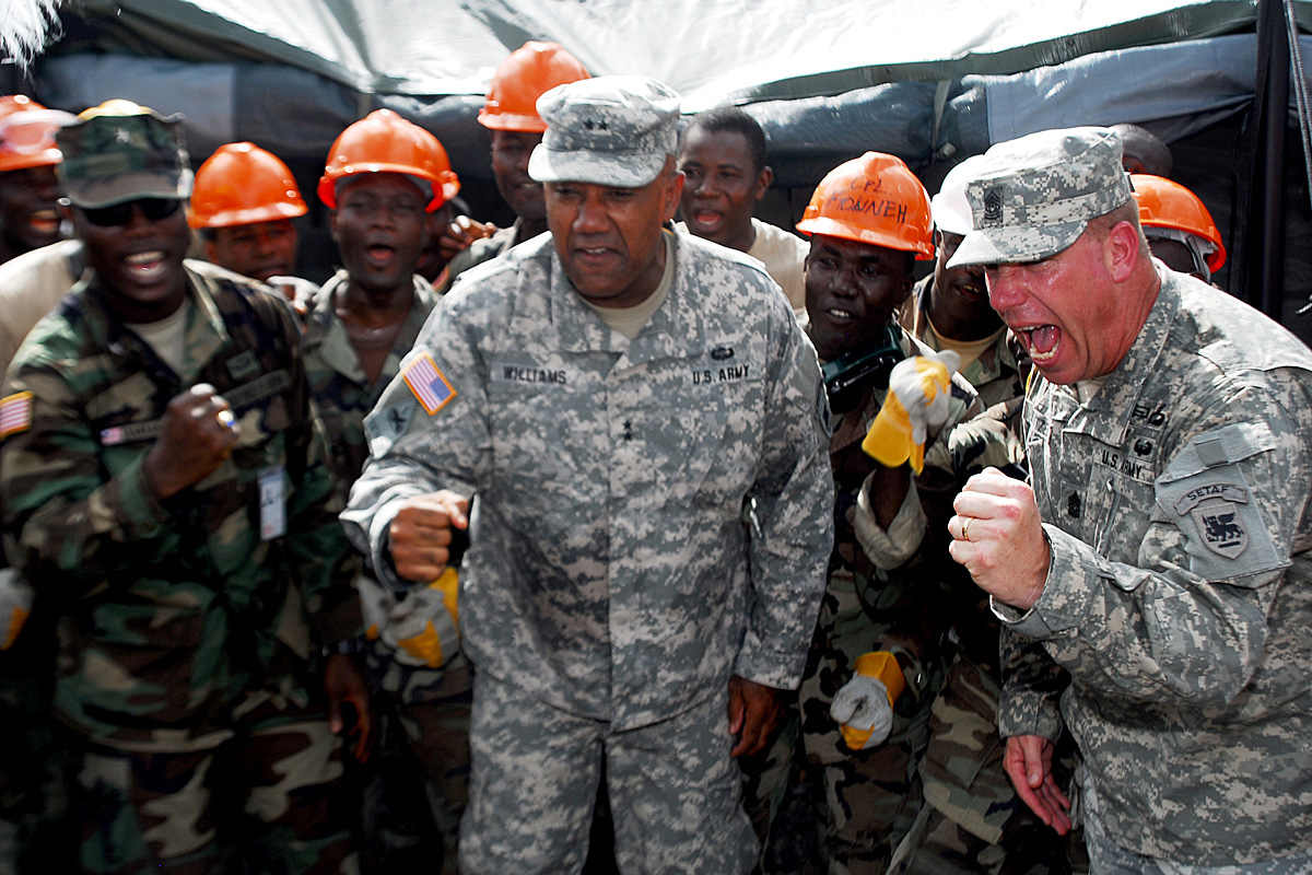 military personnel with orange helmets stand and look to the side