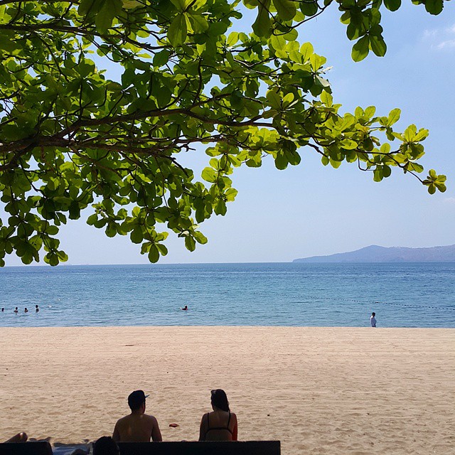 two people sitting on a bench in front of the ocean