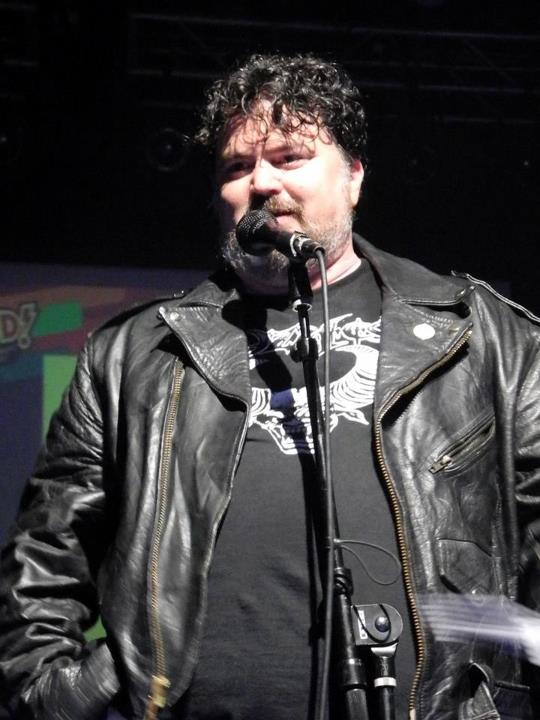 the man is speaking into the microphone at a concert
