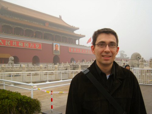 the man is standing outside in front of a large building