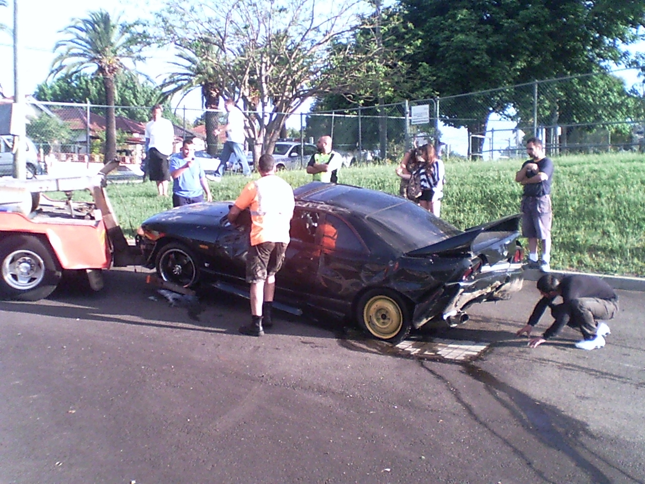 a person is leaning on a car on the road with people in the background