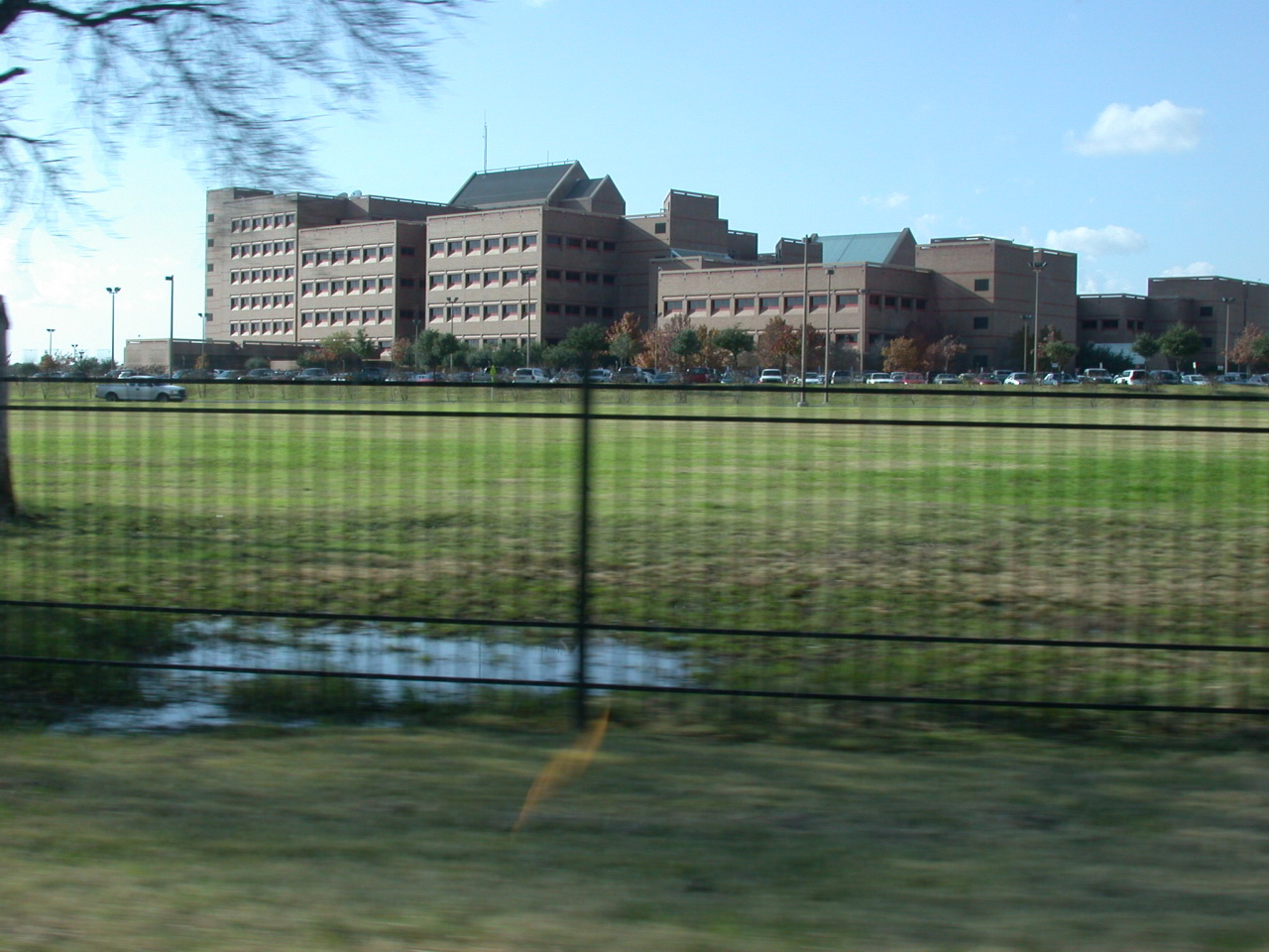 a large brown building behind a fence with water