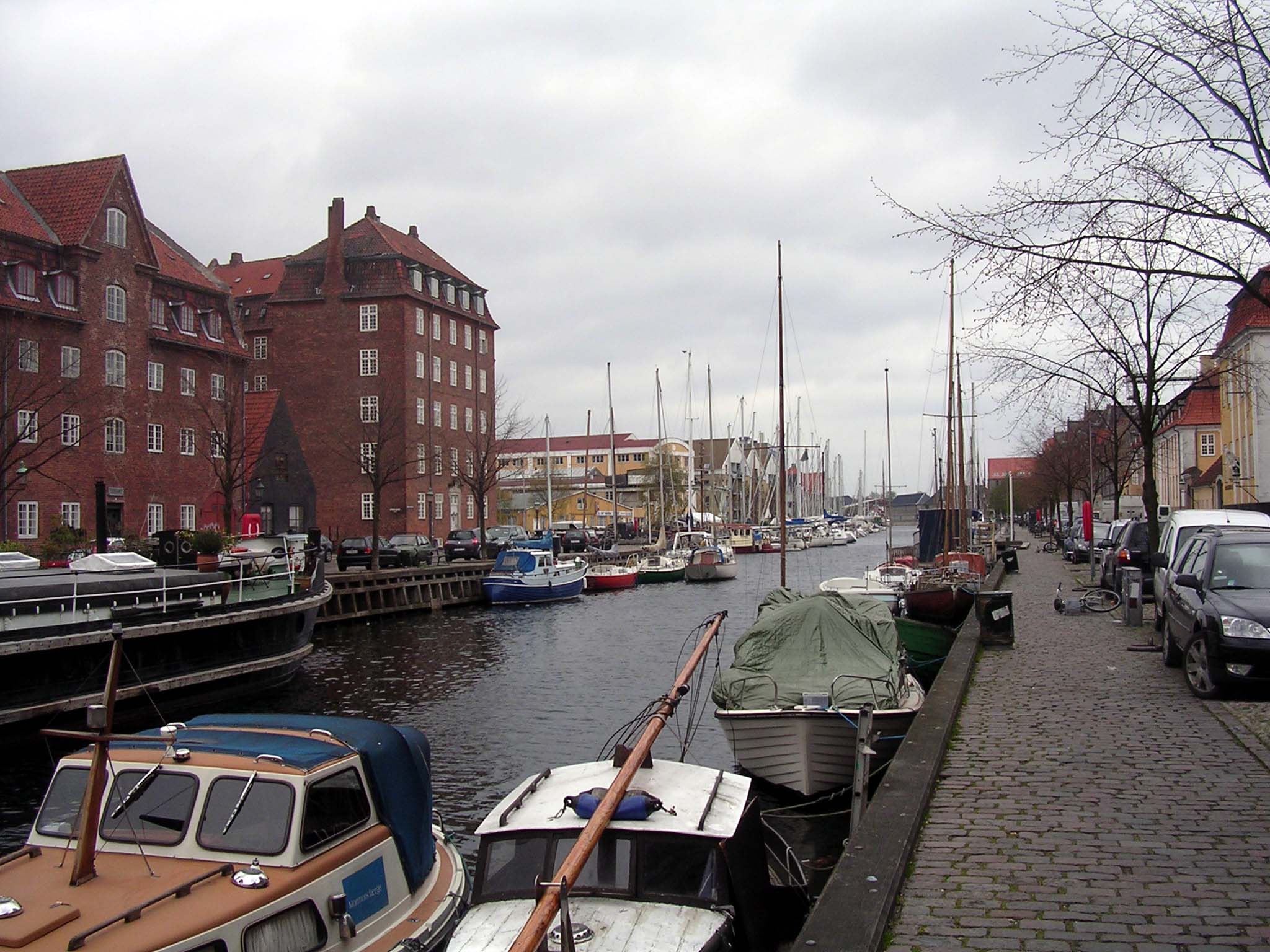 several boats sitting in the water near a street