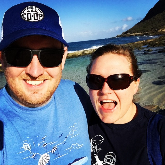 a man and woman standing next to each other on a beach