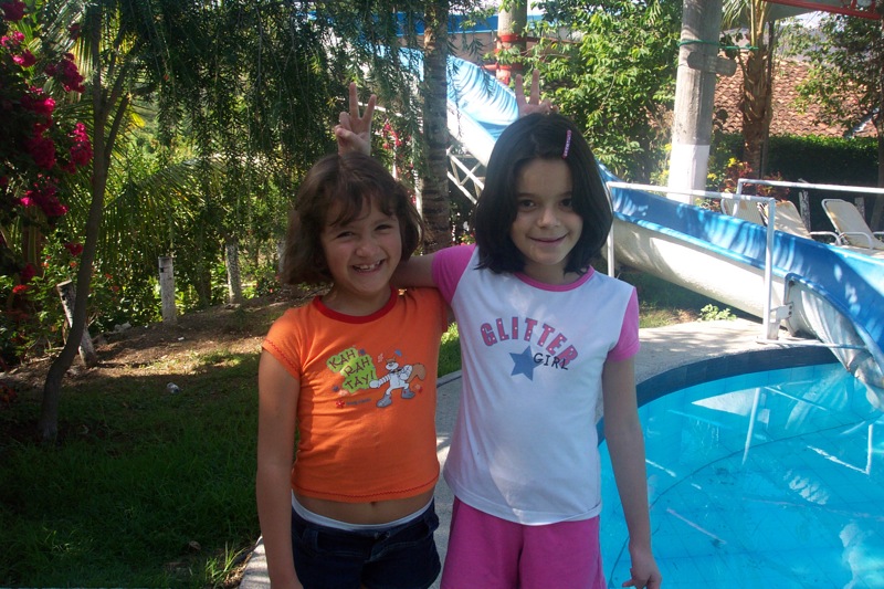 two s are posing for the camera in front of a water slide