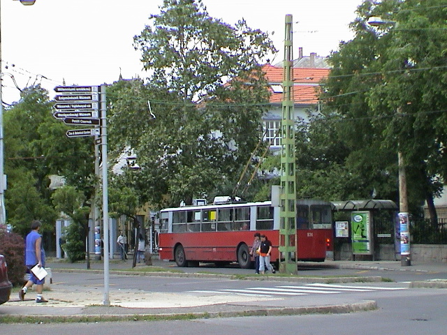 two people crossing the street at an intersection with two buses