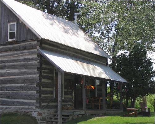 an old log cabin with a metal roof