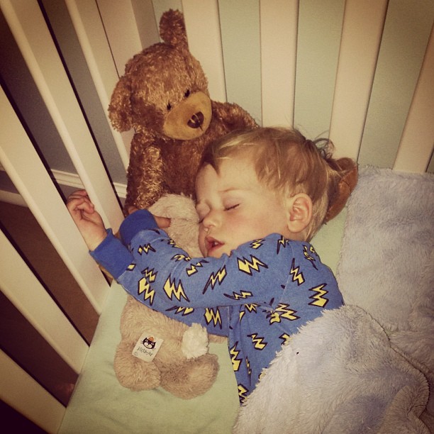 a small baby sleeping next to two stuffed bears