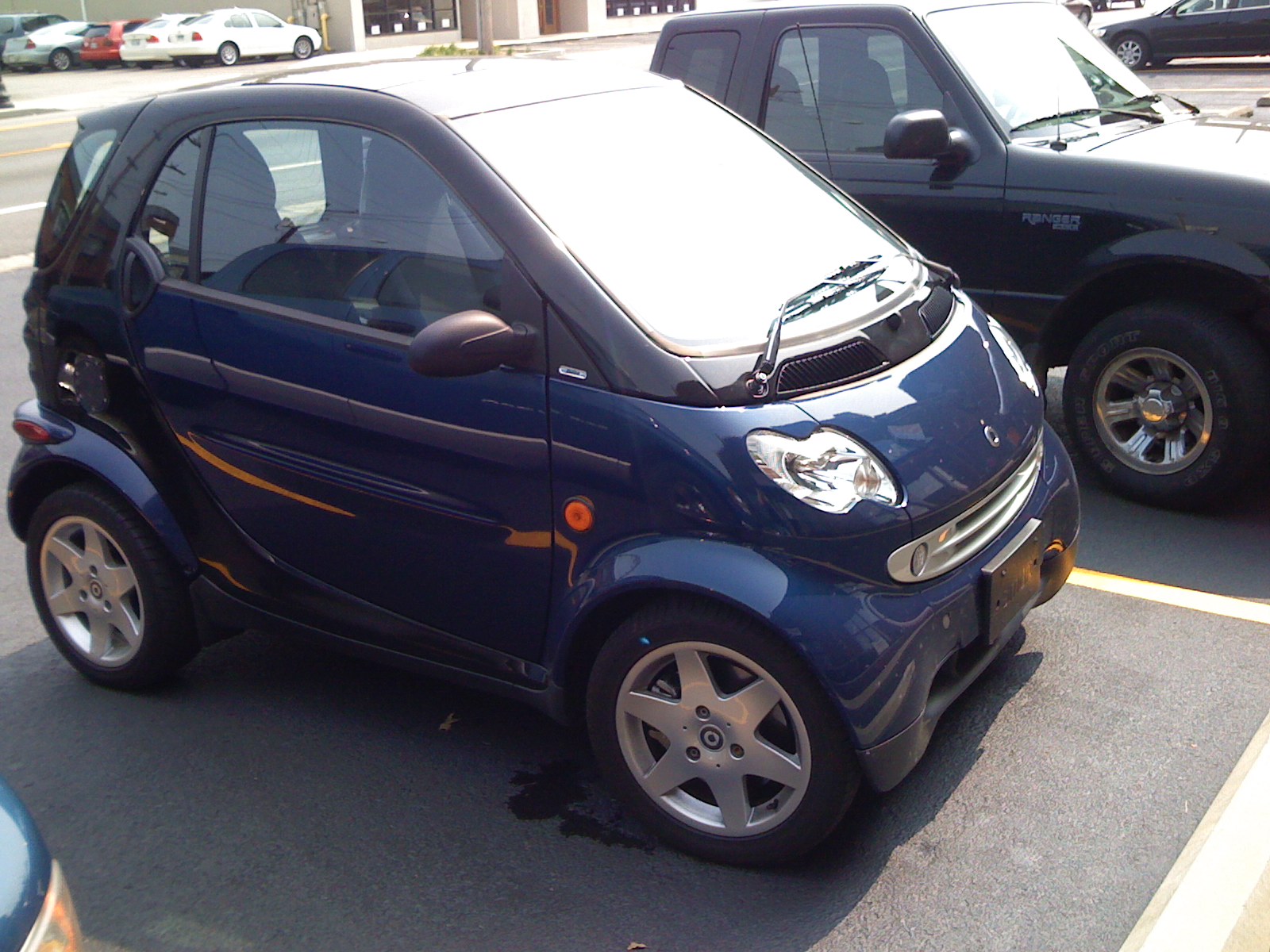 a small, compact blue car sits in the parking lot beside another small automobile