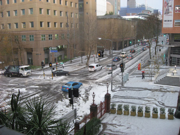 cars sit parked in the snow at an intersection