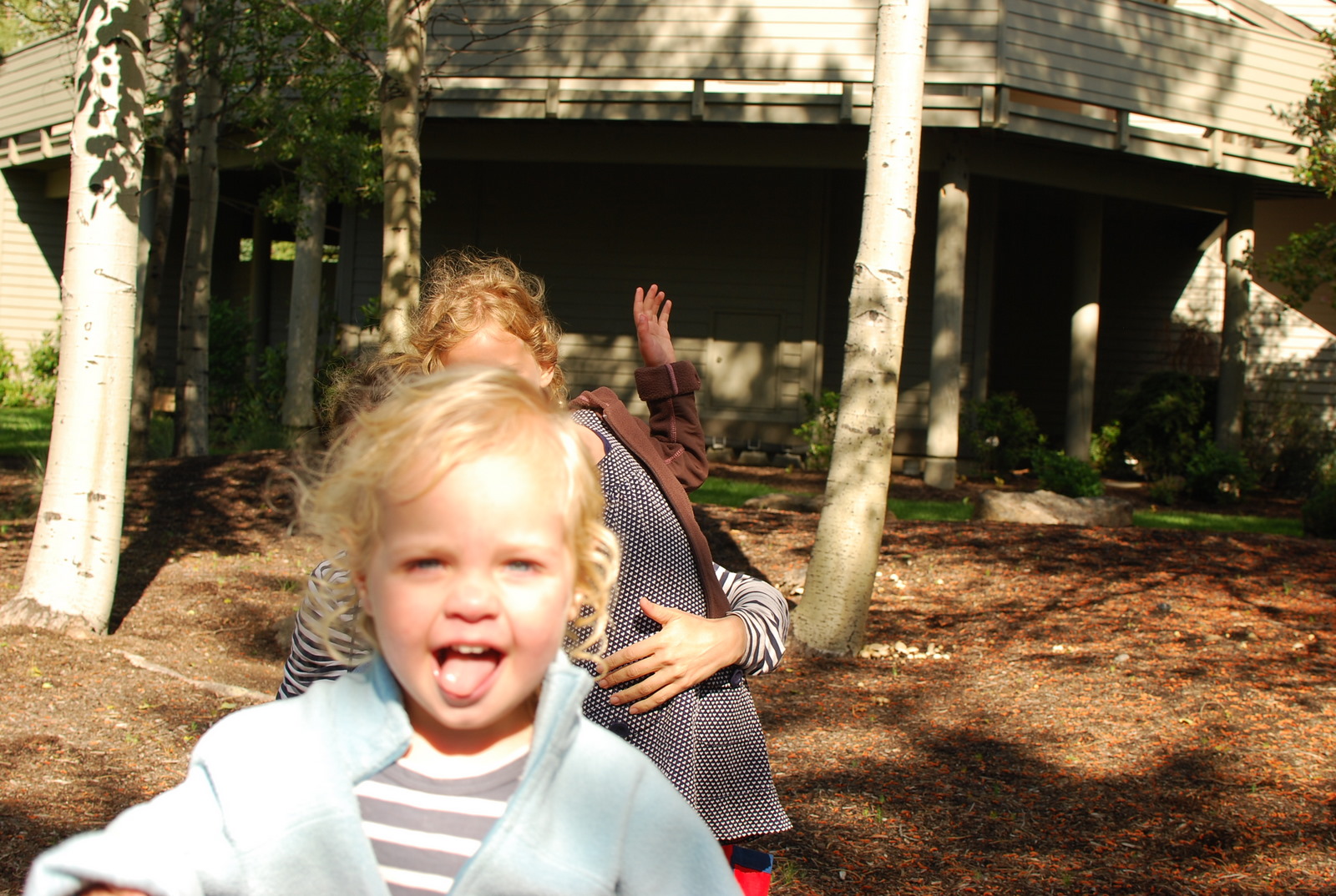 young blond haired girl making face next to woman