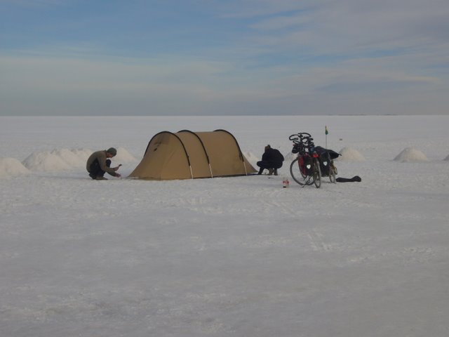 a bike is parked in the snow near a small tent and some tents