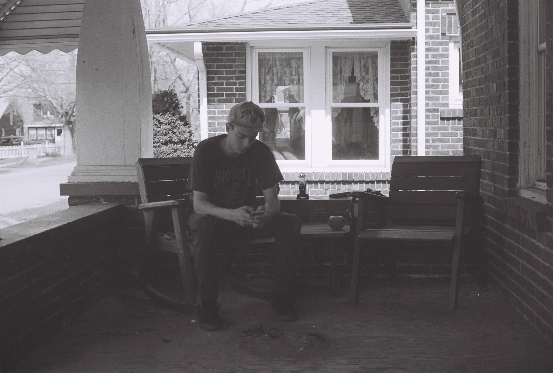 black and white image of man sitting on porch with arm resting