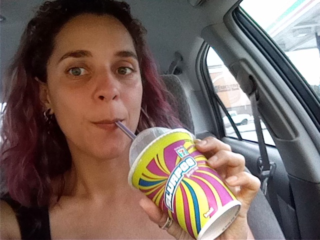 a woman is sitting in a car and drinking from a cup