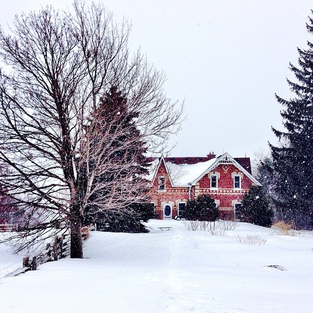 a large red house surrounded by trees covered in snow