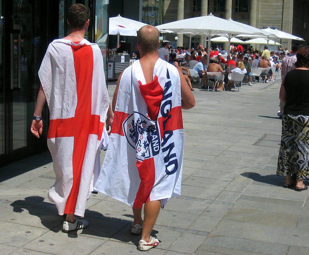 two men walking on the sidewalk holding their towel