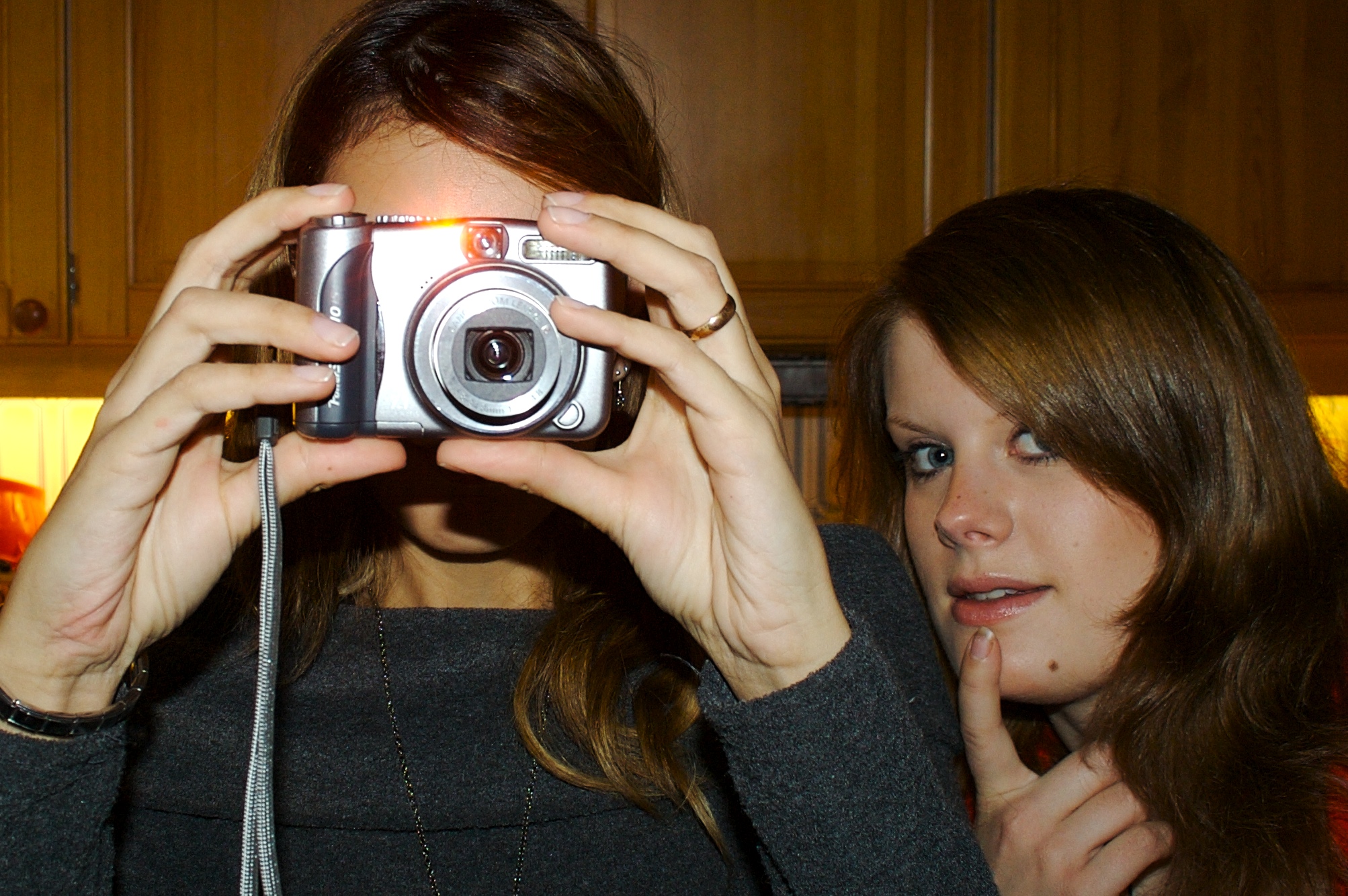 two women taking pictures with their camera in the kitchen