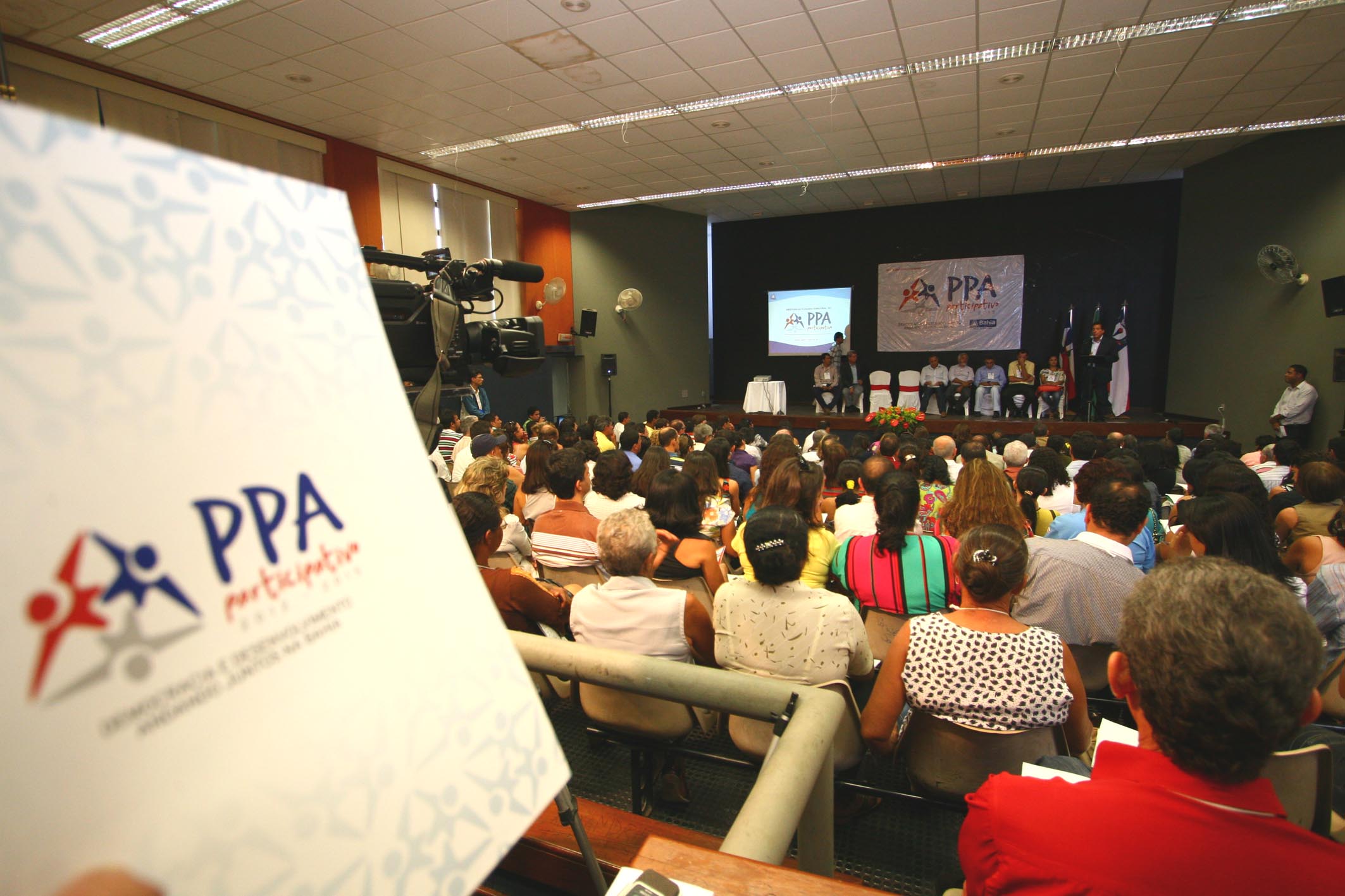 a crowd at a conference room listening to speakers