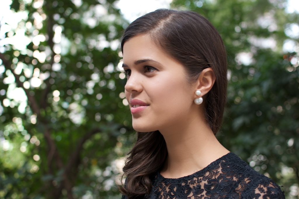 a young woman in black dress and pearls