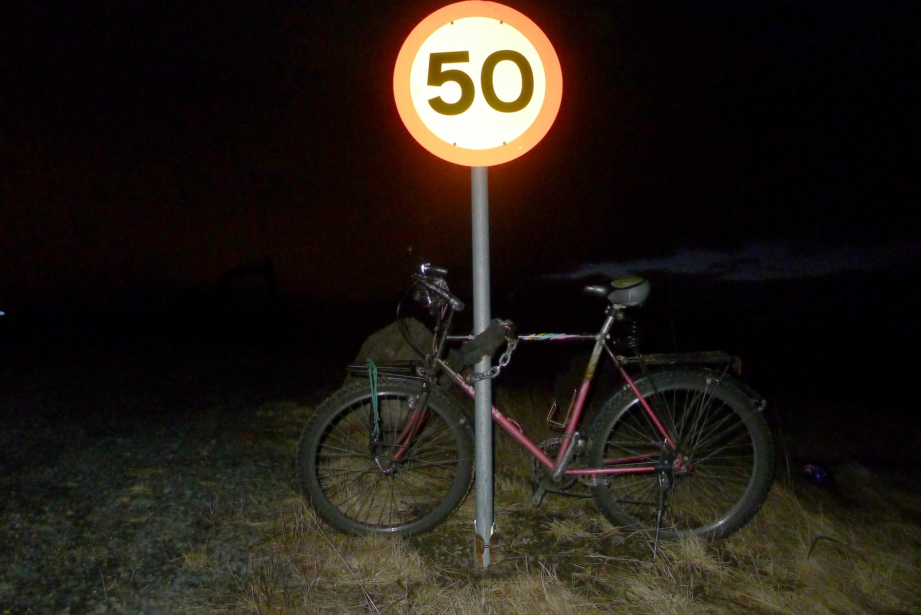 bike leans against a pole with an illuminated sign