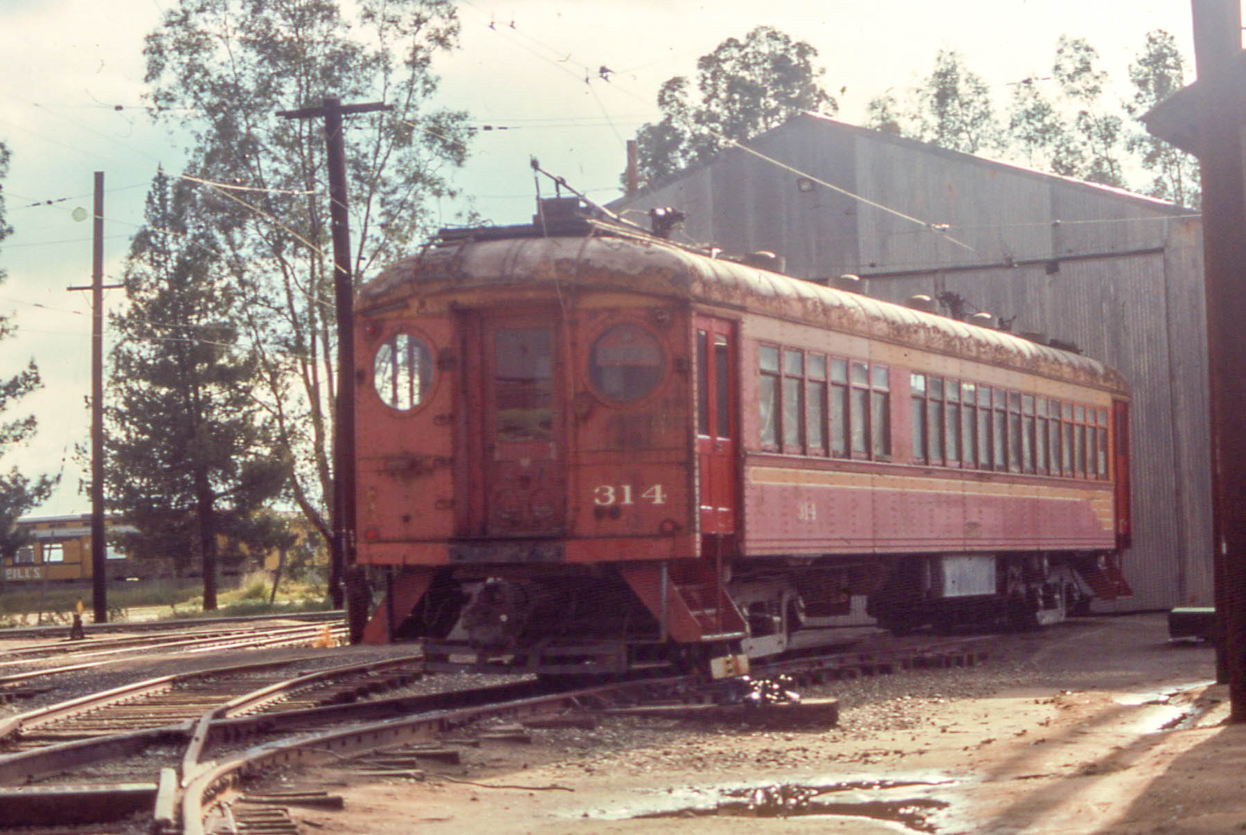 an old red train with lots of windows sitting on the tracks