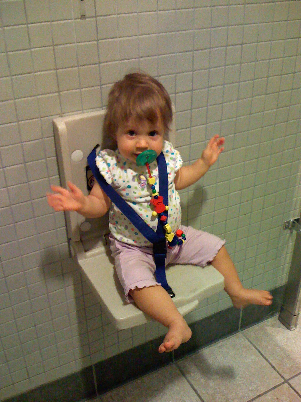 a child is sitting on a wall mounted to a toilet