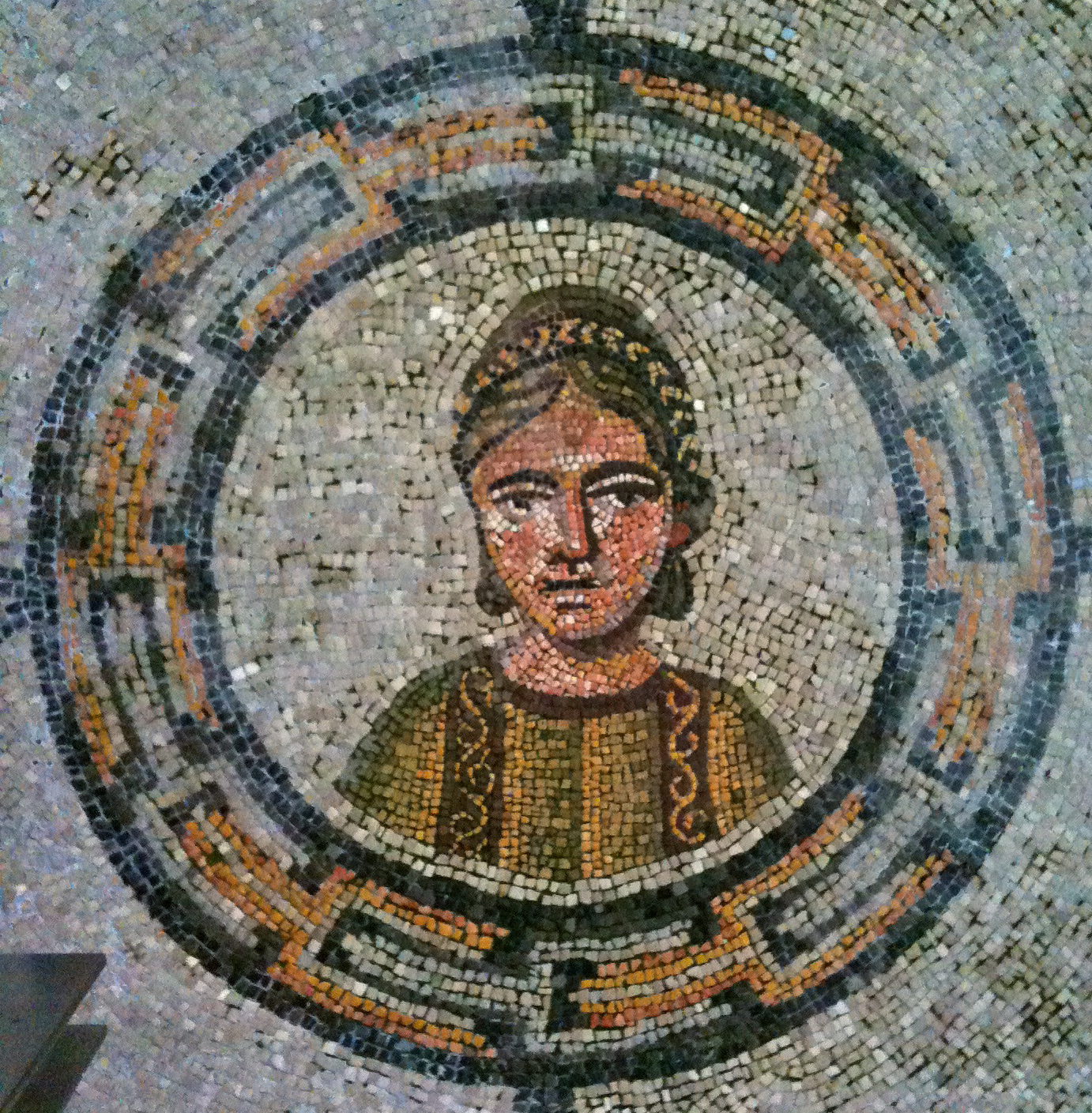 a woman in yellow standing inside a circular tile wall