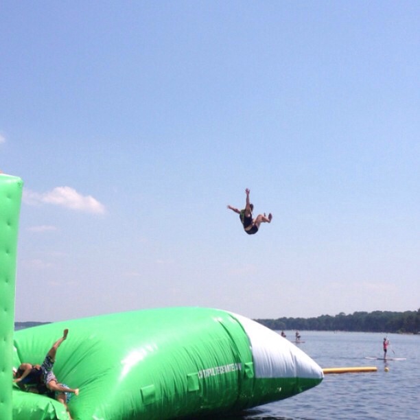 a person in the air above a body of water with an inflatable float