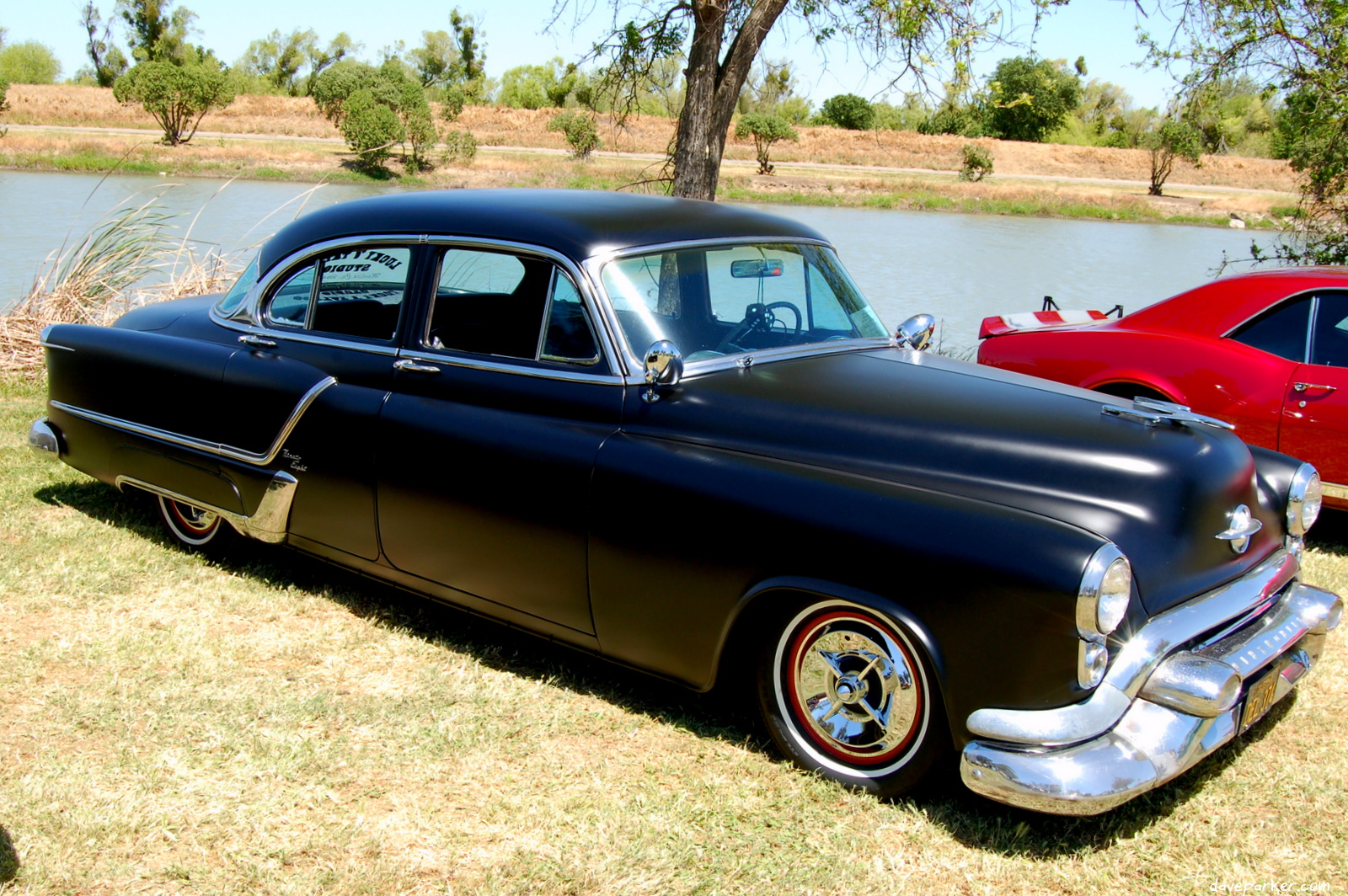 an old black car in the grass near another car