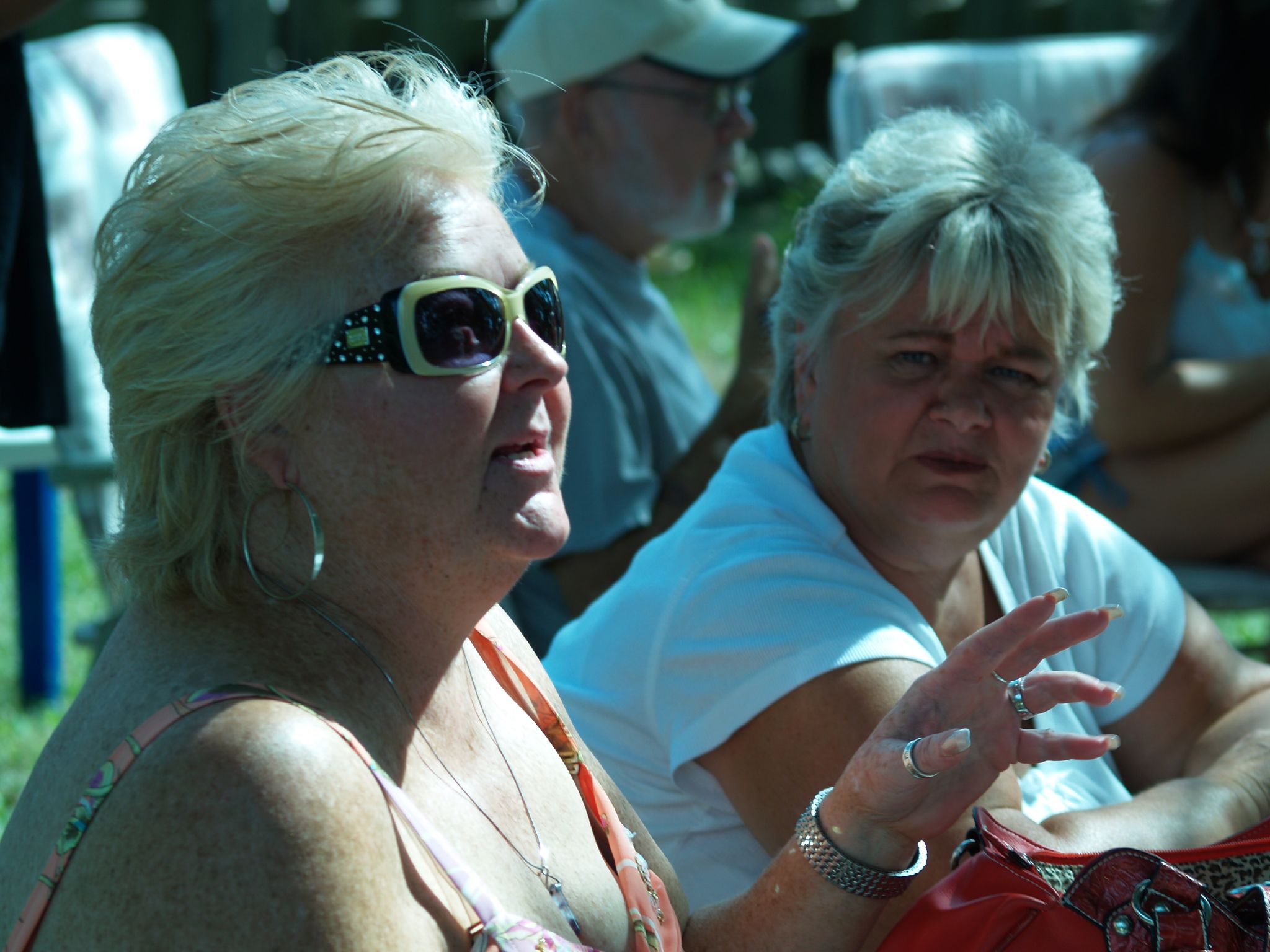 a couple of woman sitting next to each other on a field