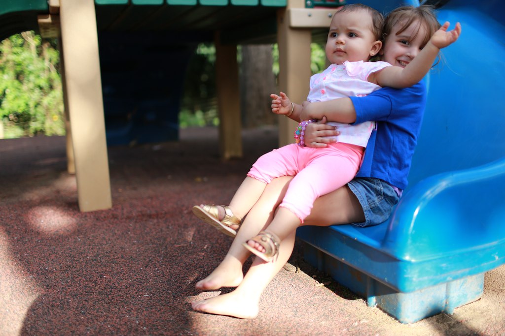 there is a small child and a smaller toddler on the swing