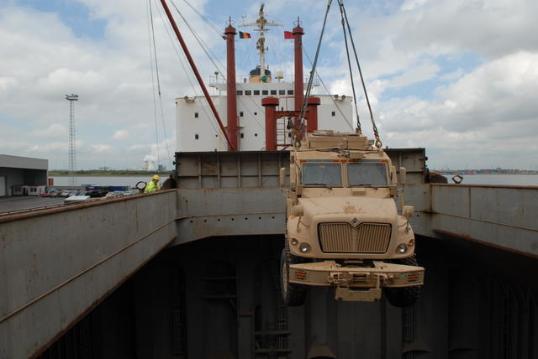 an army vehicle is loaded into the cargo ship