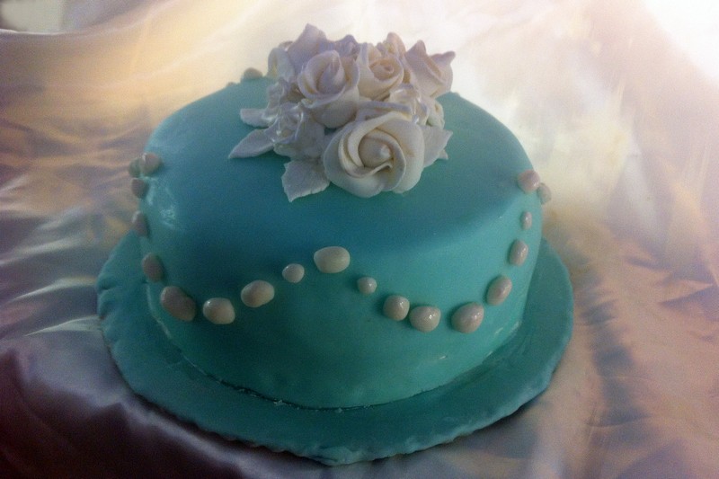 a blue cake on a table covered with white roses