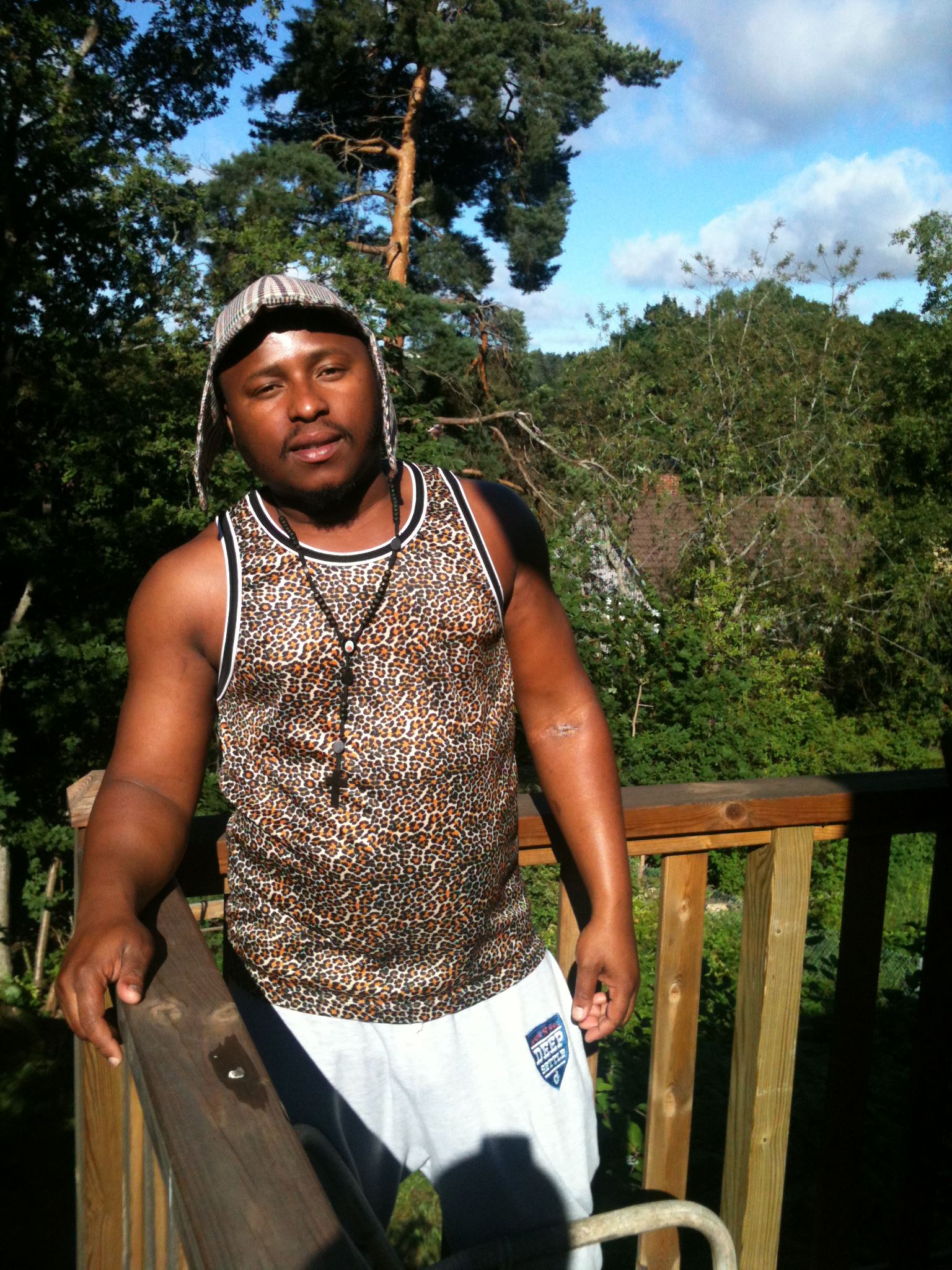 a man in a tank top and shorts holding a skateboard on a porch